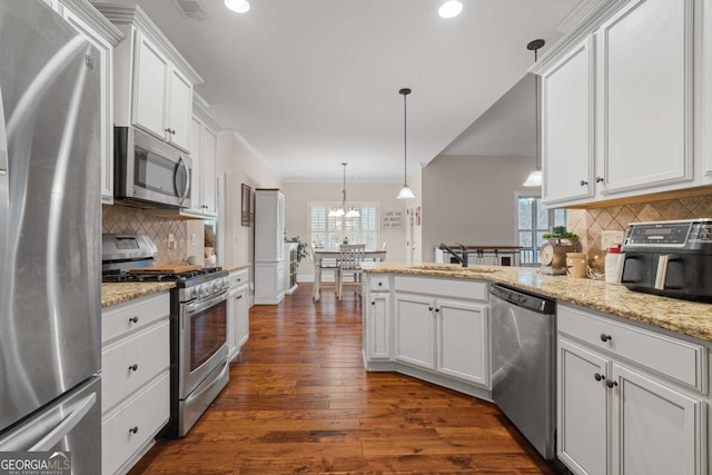 kitchen featuring stainless steel appliances, dark wood-type flooring, a peninsula, a sink, and white cabinetry