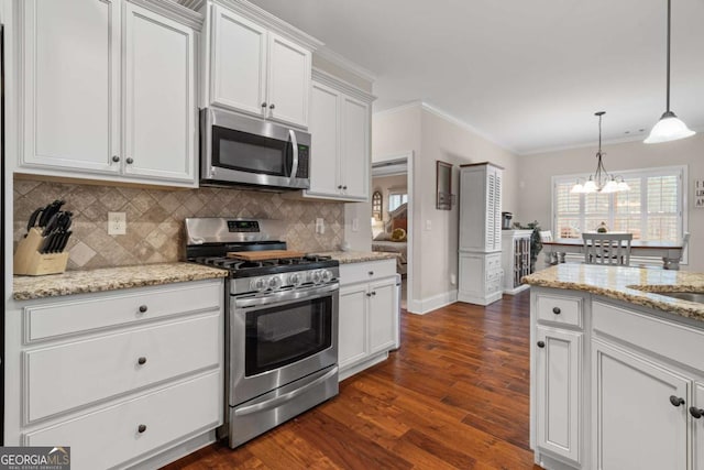 kitchen featuring white cabinets, ornamental molding, appliances with stainless steel finishes, tasteful backsplash, and dark wood finished floors