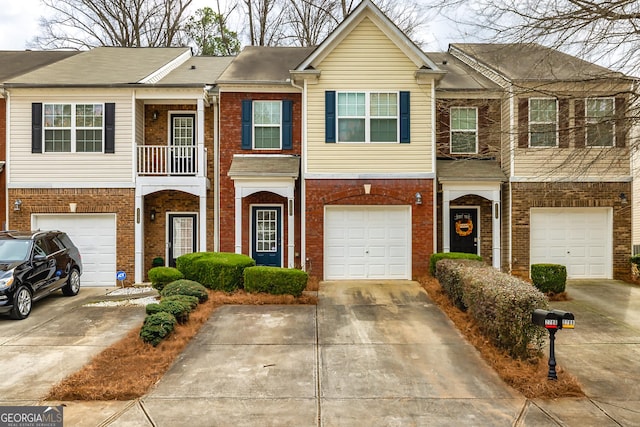 townhome / multi-family property with driveway, a balcony, an attached garage, and brick siding