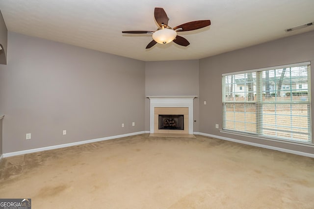 unfurnished living room with light carpet, visible vents, baseboards, a fireplace with flush hearth, and ceiling fan