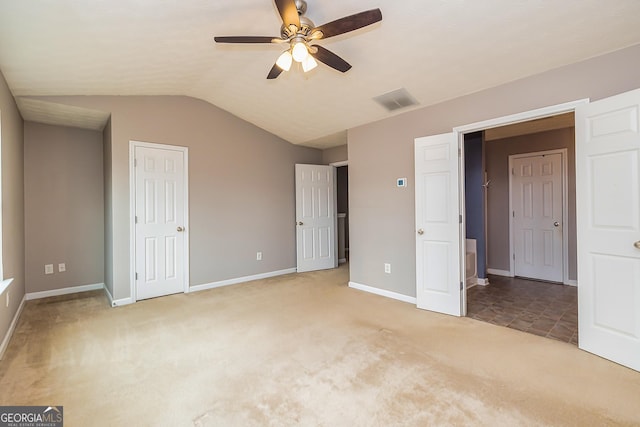 unfurnished bedroom featuring ceiling fan, light colored carpet, visible vents, baseboards, and vaulted ceiling