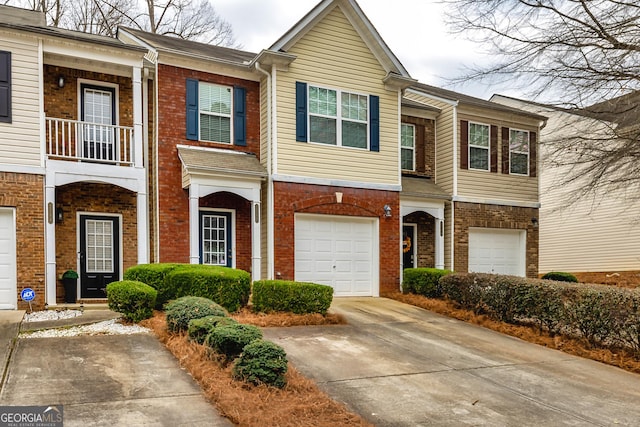 townhome / multi-family property with a garage, concrete driveway, and brick siding