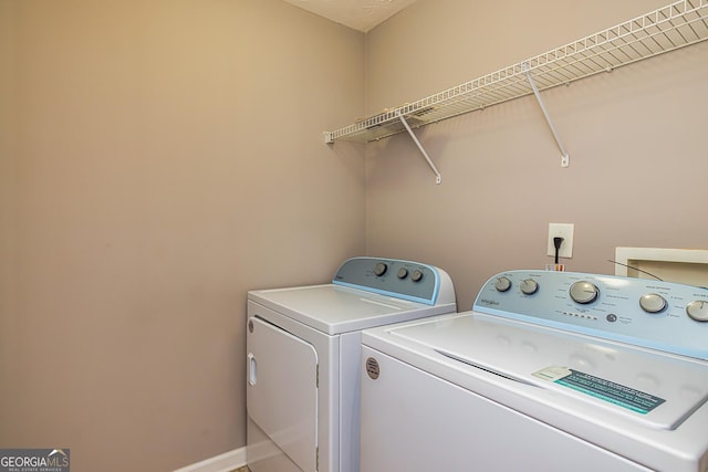 clothes washing area with laundry area, washing machine and dryer, and baseboards