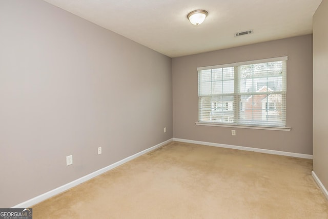 empty room with light colored carpet, visible vents, and baseboards