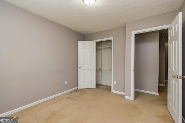 unfurnished bedroom with baseboards, a textured ceiling, a closet, and light colored carpet