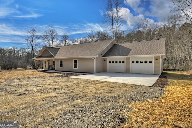 view of front facade featuring a garage, driveway, and a shingled roof