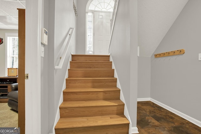 stairs with stone finish floor, baseboards, and a drop ceiling