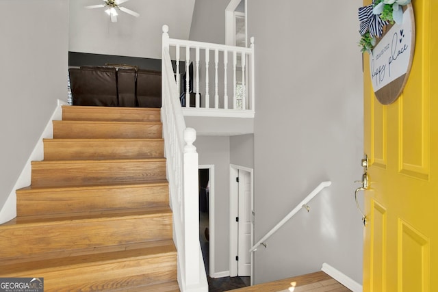 staircase featuring a ceiling fan and a high ceiling