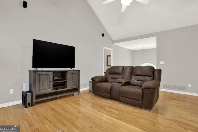 living room featuring light wood finished floors, visible vents, a ceiling fan, high vaulted ceiling, and baseboards