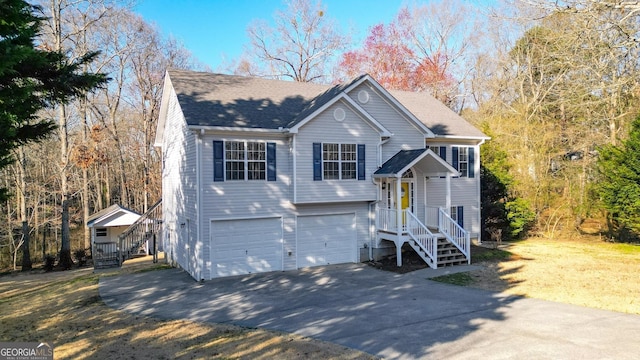 split foyer home featuring driveway, roof with shingles, and an attached garage