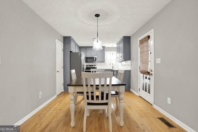 dining room featuring baseboards, visible vents, and light wood finished floors