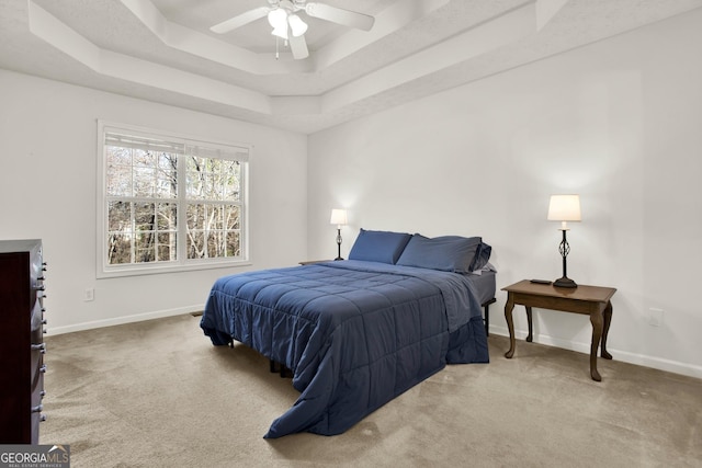 bedroom featuring carpet, baseboards, a raised ceiling, and a ceiling fan