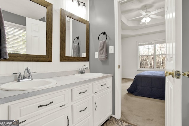 ensuite bathroom featuring double vanity, ceiling fan, connected bathroom, and a sink