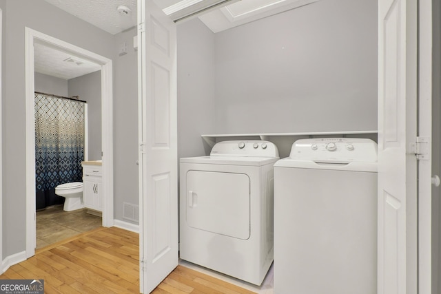 laundry room featuring light wood-type flooring, laundry area, visible vents, and washing machine and clothes dryer