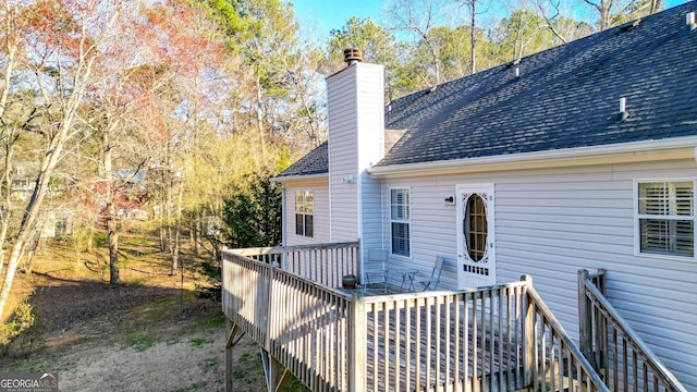 back of house with a deck, roof with shingles, and a chimney