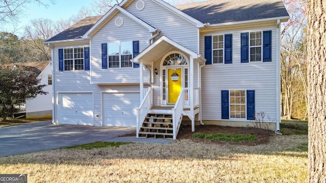 raised ranch featuring aphalt driveway, roof with shingles, and an attached garage