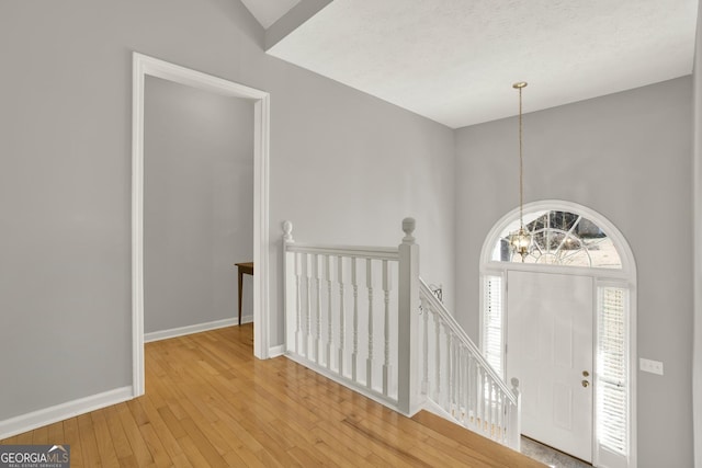 entrance foyer with baseboards, wood-type flooring, and a notable chandelier