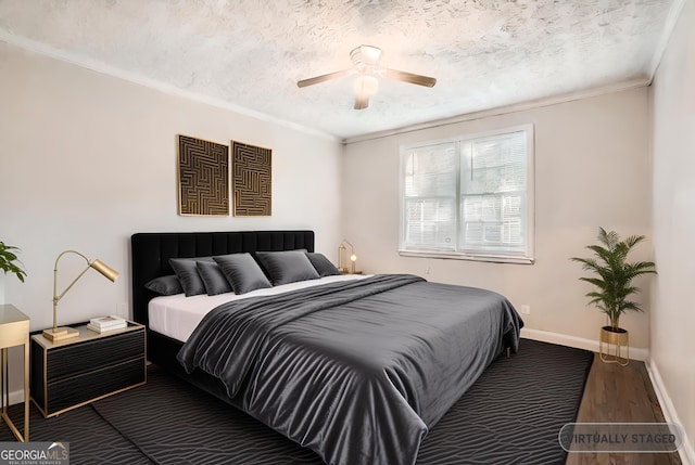 bedroom with a textured ceiling, wood finished floors, a ceiling fan, baseboards, and ornamental molding