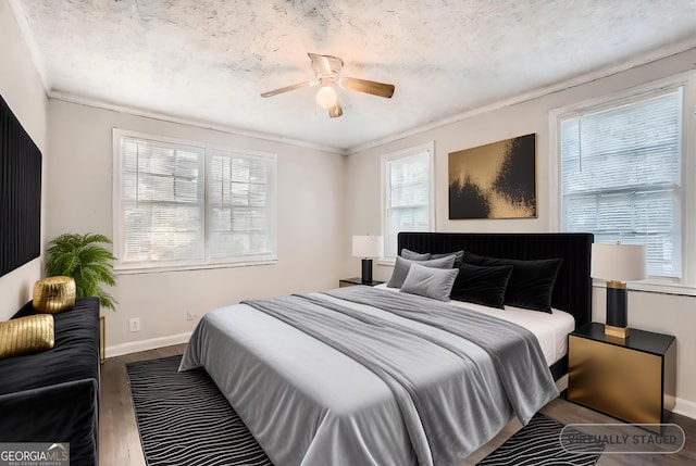 bedroom with a ceiling fan, a textured ceiling, baseboards, and wood finished floors