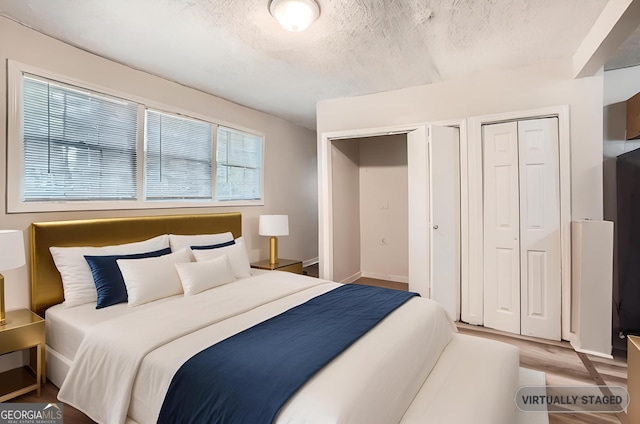 bedroom with baseboards, a textured ceiling, and wood finished floors