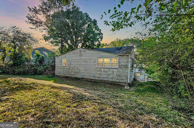 property exterior at dusk featuring a lawn