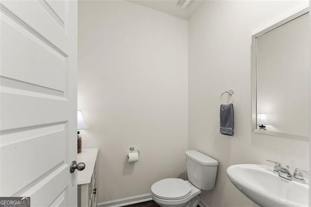 half bathroom with a sink, toilet, and baseboards