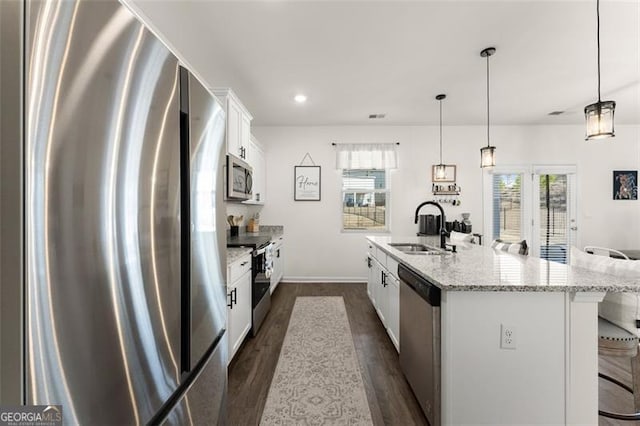 kitchen with a breakfast bar, dark wood-style flooring, appliances with stainless steel finishes, white cabinetry, and a sink