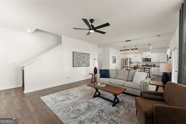 living room featuring recessed lighting, dark wood-style flooring, a ceiling fan, baseboards, and stairs