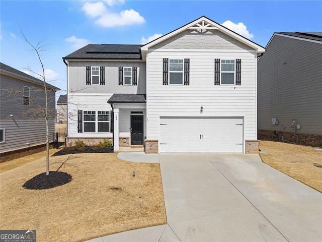 view of front of property featuring driveway, solar panels, an attached garage, board and batten siding, and a front yard