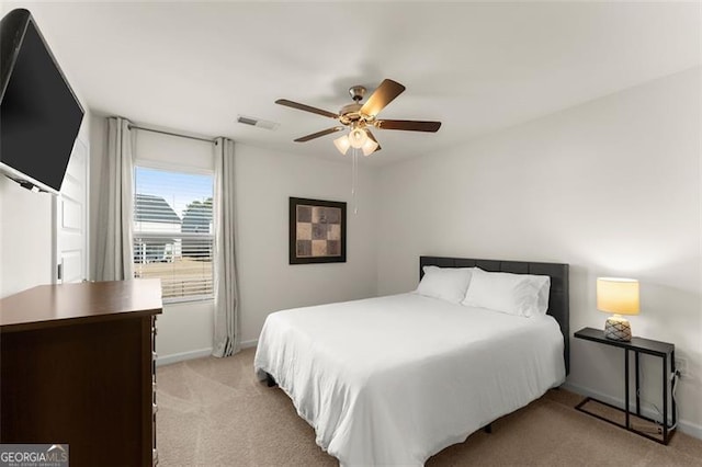 bedroom with light carpet, ceiling fan, visible vents, and baseboards