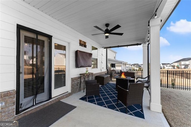 view of patio / terrace with fence, a fire pit, and a ceiling fan