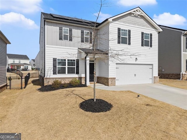 traditional home with driveway, solar panels, an attached garage, fence, and board and batten siding