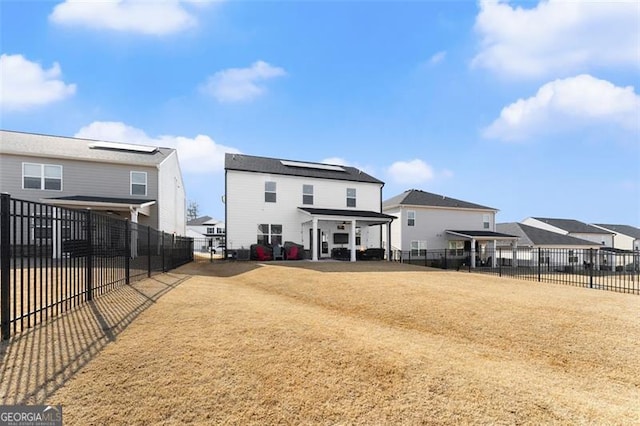 back of house featuring a fenced backyard and roof mounted solar panels