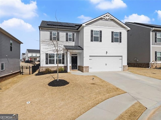 view of front of home featuring driveway, a garage, roof mounted solar panels, and fence