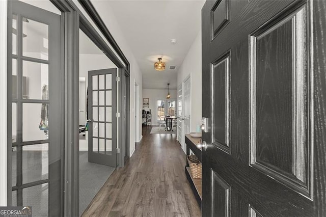 hallway with french doors, visible vents, and wood finished floors