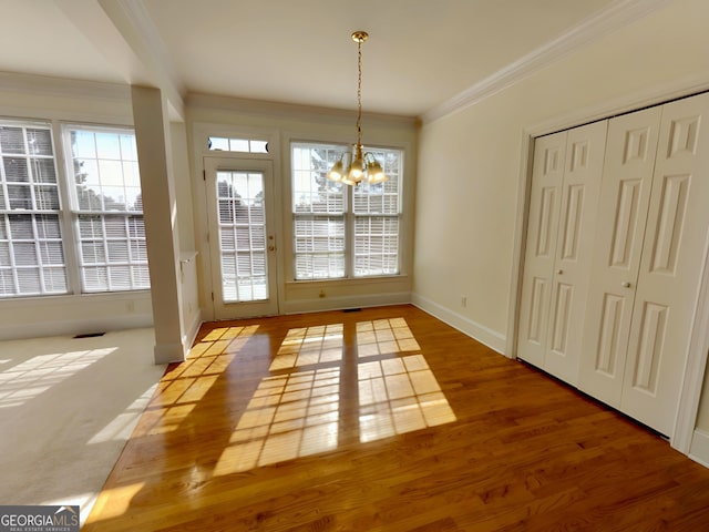 unfurnished dining area featuring a chandelier, ornamental molding, wood finished floors, and baseboards