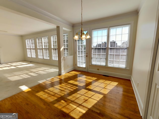 interior space featuring an inviting chandelier, baseboards, crown molding, and wood finished floors