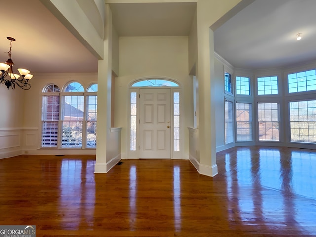 entrance foyer featuring a chandelier, a wealth of natural light, a decorative wall, and wood finished floors