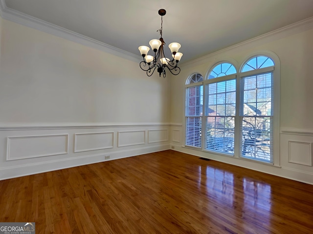 interior space featuring a chandelier, wood finished floors, visible vents, wainscoting, and crown molding