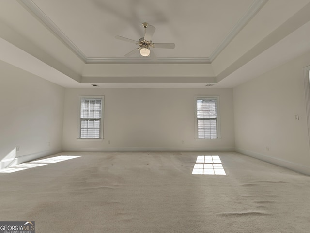 unfurnished room with ornamental molding, a tray ceiling, light carpet, and baseboards