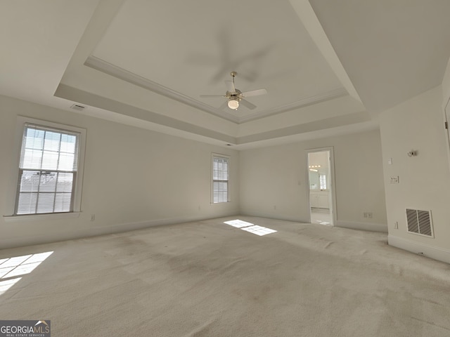 unfurnished room featuring ceiling fan, light carpet, visible vents, baseboards, and a raised ceiling