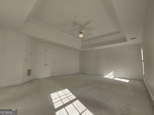 empty room featuring a tray ceiling, visible vents, and baseboards