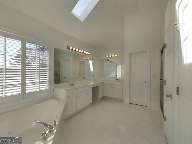 bathroom with a skylight, high vaulted ceiling, a garden tub, and vanity