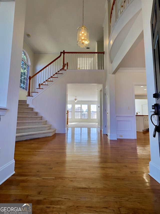 foyer entrance featuring stairway, plenty of natural light, wood finished floors, and an inviting chandelier