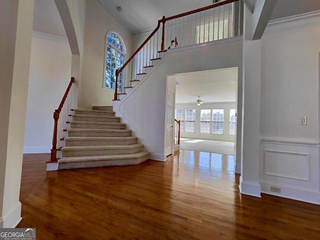 interior space with ornamental molding, ceiling fan, baseboards, and wood finished floors