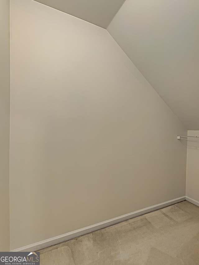 bonus room featuring lofted ceiling, light carpet, and baseboards