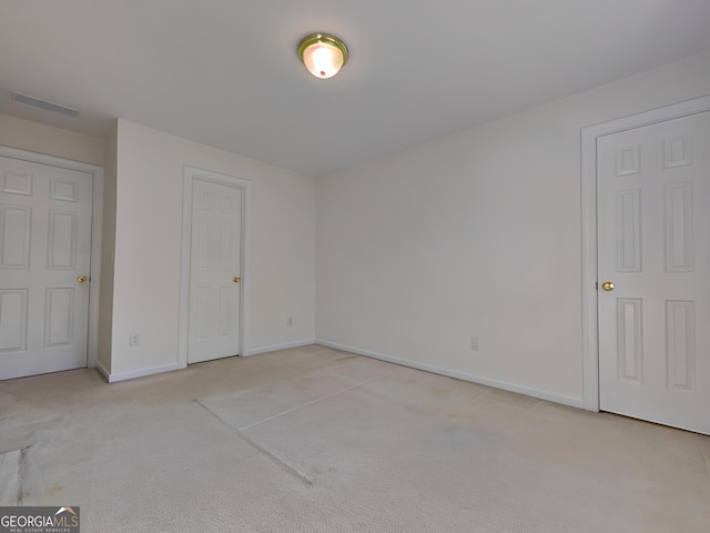 unfurnished bedroom featuring light colored carpet, visible vents, and baseboards