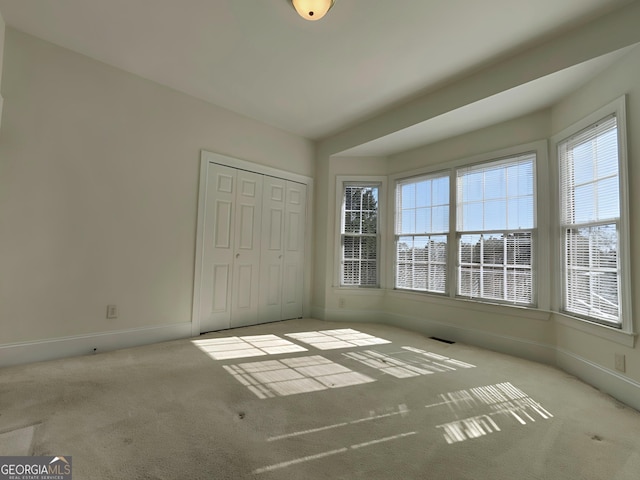 unfurnished bedroom with carpet floors, a closet, visible vents, and baseboards