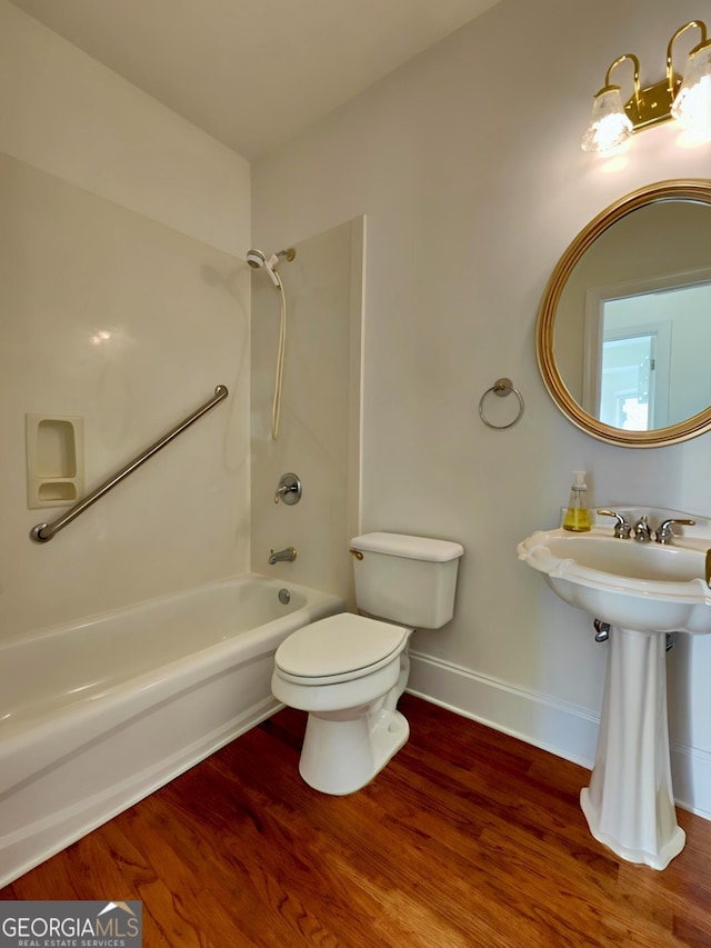 full bath with shower / washtub combination, wood finished floors, toilet, and baseboards