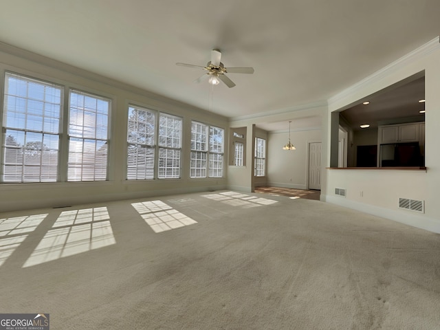 unfurnished living room featuring baseboards, visible vents, ornamental molding, carpet flooring, and ceiling fan with notable chandelier